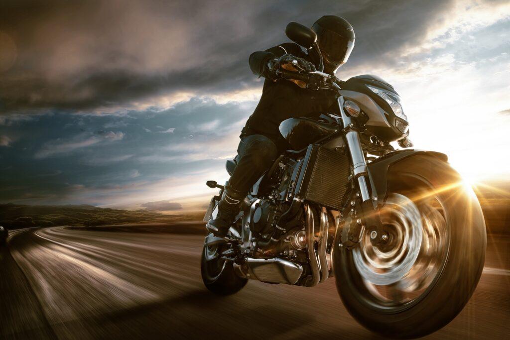 Motorradfahrer legt sich in Kurve bei Sonnenuntergang | BMW R 1300 GS