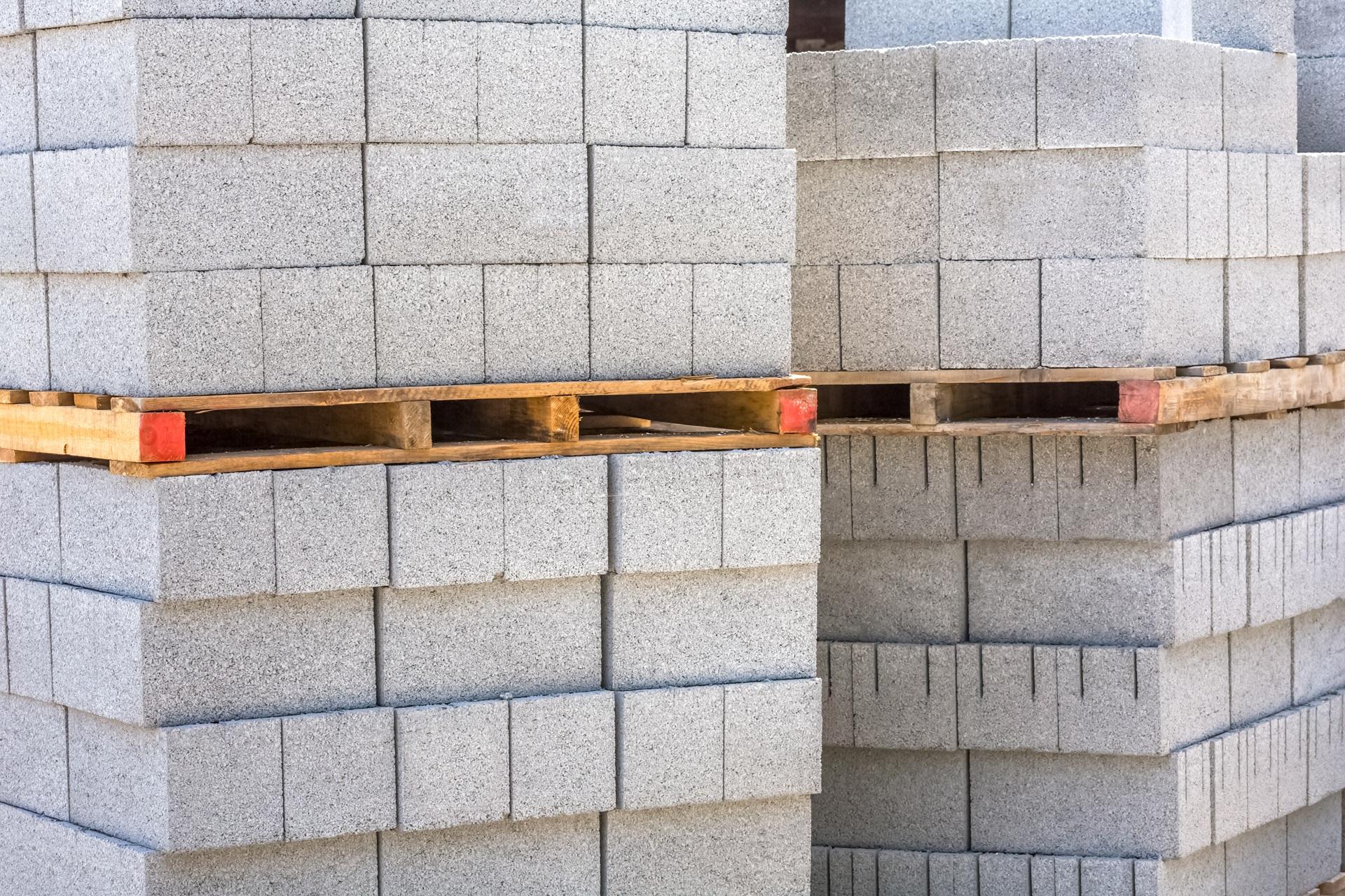 Gestapelte graue Betonsteine auf Holzpaletten | Heizcontainer